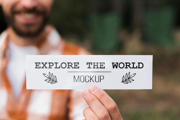front view of defocused smiley man holding a piece of paper while camping