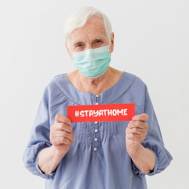 Front view of elder woman with medical mask holding message