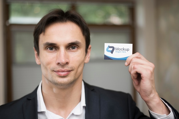 Front view of handsome businessman holding business card