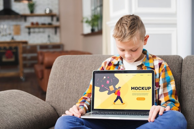 PSD front view of kid on couch holding laptop