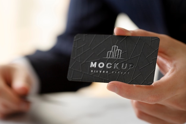 Front view man holding business card with silver logo
