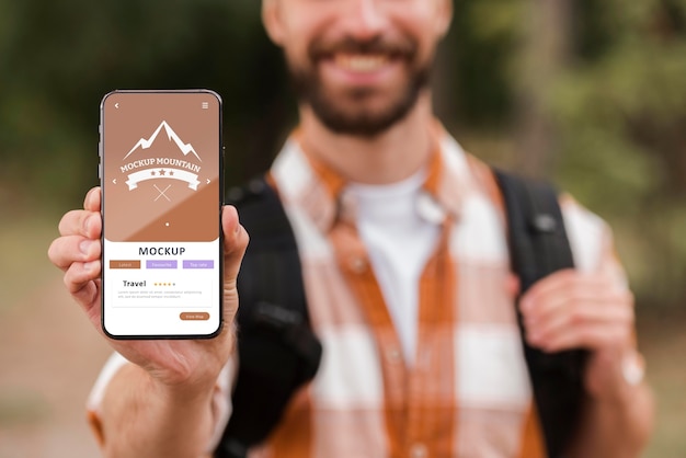 PSD front view of smiley man holding smartphone while camping