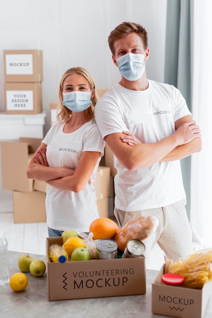front view of volunteers with medical masks posing with donation boxes