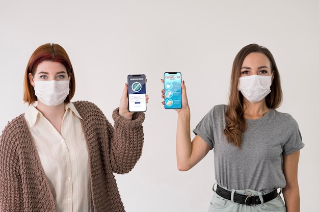 PSD front view of women with masks holding smartphones