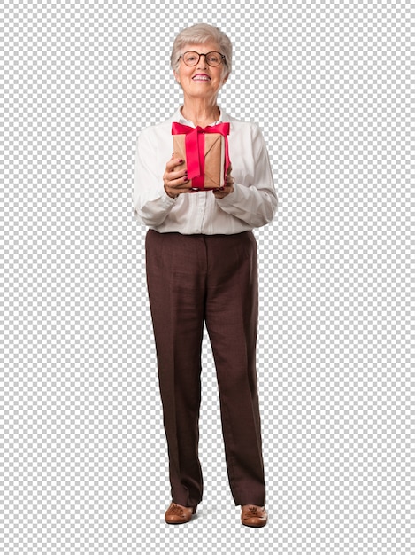 Full body senior woman happy and smiling, holding a nice gift, excited and full, celebrating a birthday or a featured event