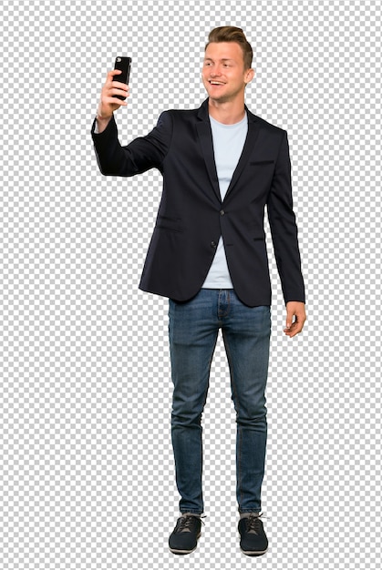 PSD a full length shot of a blonde handsome man making a selfie