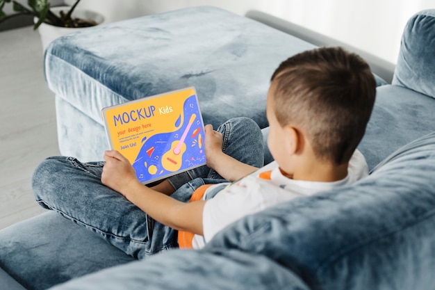 Full shot kid on couch with laptop