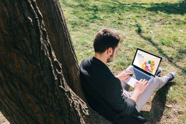 Uomo della foto a figura intera che lavora al computer portatile