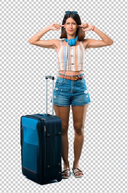 PSD girl traveling with her suitcase covering both ears with hands. frustrated expression