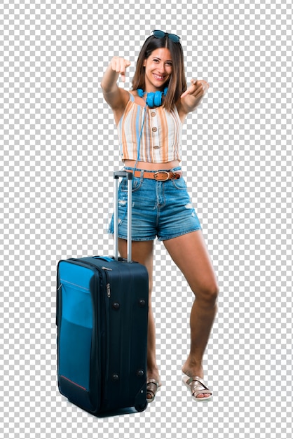 PSD girl traveling with her suitcase pointing with finger at someone and laughing a lot