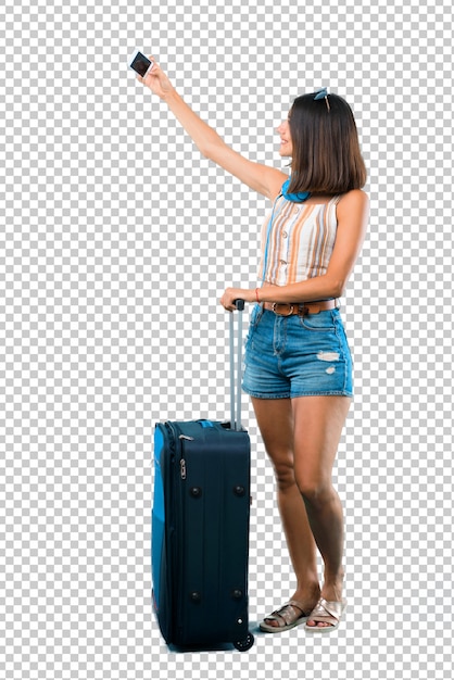 Ragazza che viaggia con la sua valigia prendendo un selfie con il cellulare