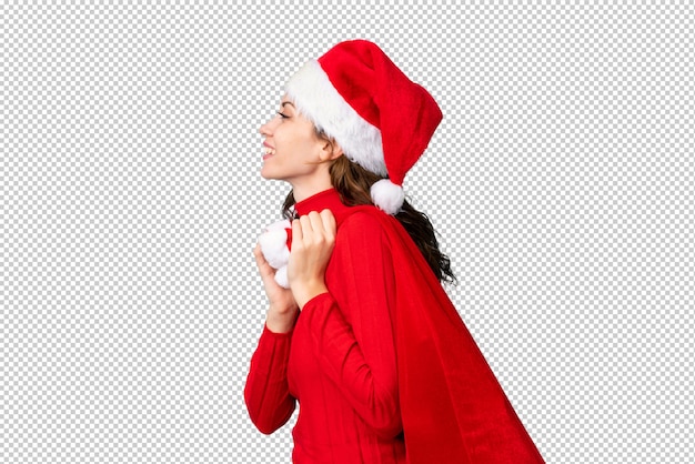 Girl with christmas hat holding a christmas bag full of gifts