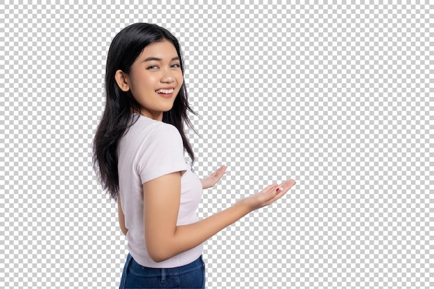 Glimlachende jonge Aziatische vrouw die met open handen en een vrolijke uitdrukking naar achteren kijkt en iets geïsoleerd op een doorzichtige achtergrond presenteert of introduceert