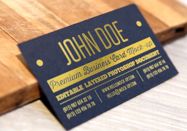 Gold letterpress on black paper business card mockup with gold letters on wooded background