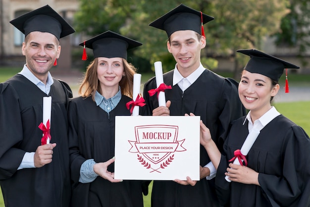 Graduates holding proudly a mock-up diploma