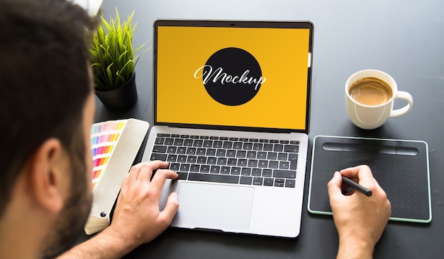 Graphic designer che lavora al mockup del laptop