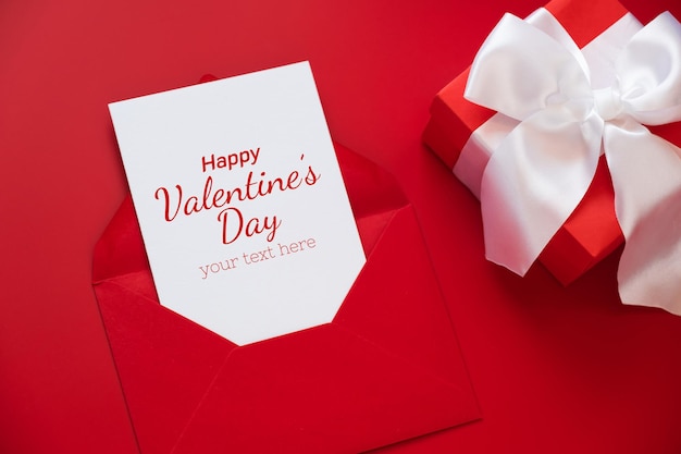 greeting card mockup, white blank card in envelope and gift box on red background.