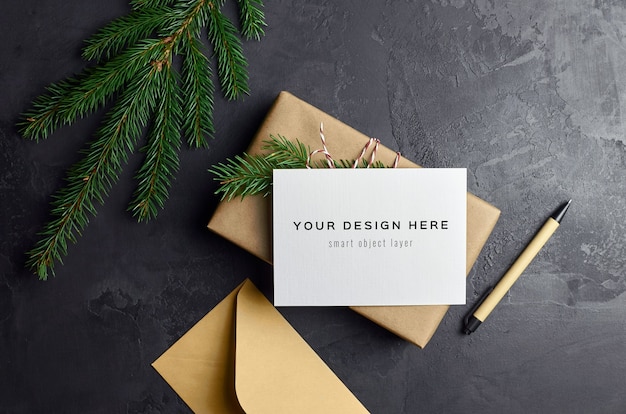 Greeting card mockup with Christmas gift box and fir tree branches on dark