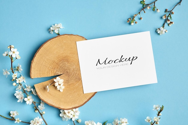 Greeting card mockup with cut log and spring cherry blossom twigs