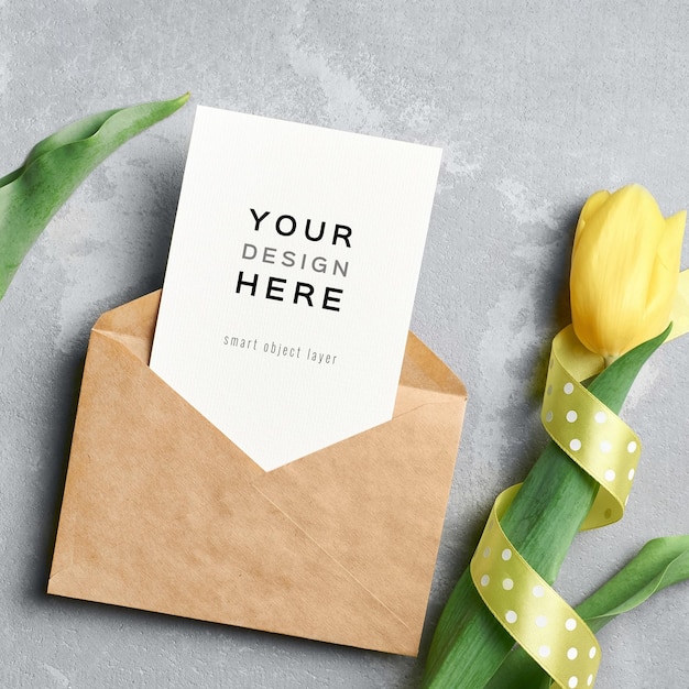 Greeting card mockup with envelope and yellow tulip flower with ribbon on grey