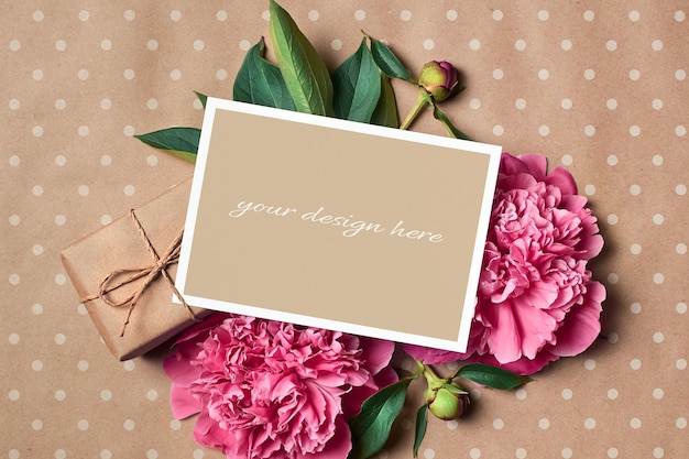 PSD Макет поздравительной открытки с подарочной коробкой и розовыми цветами пиона на фоне крафт-бумаги