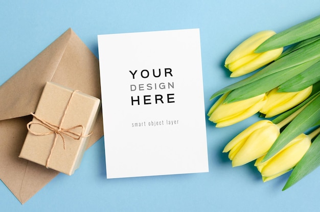 Greeting card mockup with gift box and yellow tulip flowers on blue