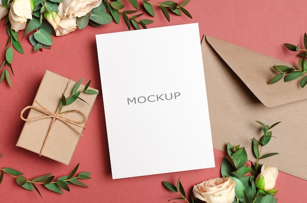 Mockup di biglietto di auguri con busta regalo e fiori di rose fresche