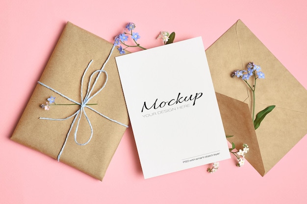 Greeting card mockup with gift, envelope and spring forget-me-not flowers on pink