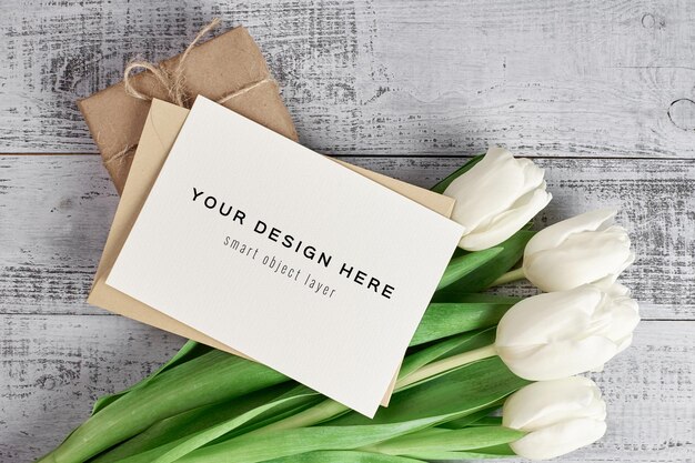 Greeting card mockup with tulip flowers and gift box on wooden