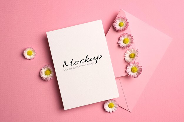 Mockup di auguri o invito o biglietto con busta e fiori margherita su rosa