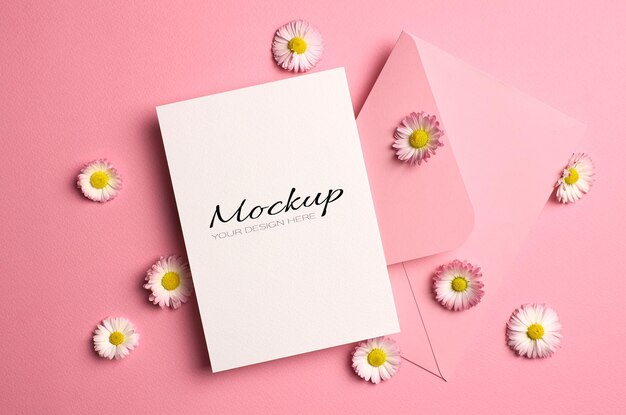 Mockup di auguri o invito o carta con busta e fiori a margherita su rosa