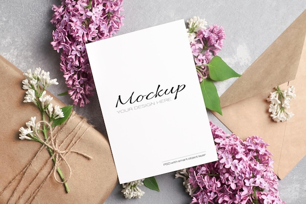 Greeting or invitation card mockup with gift box, envelope and lilac flowers