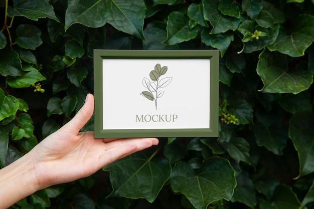 Mano che tiene mockup cornice verde