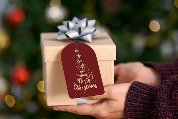 Рука держит макет рождественской открытки и подарочной коробки