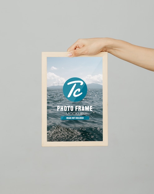 Hand holding photo frame mockup template for your design.