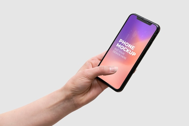 Hand holding smartphone device mock-up on color background