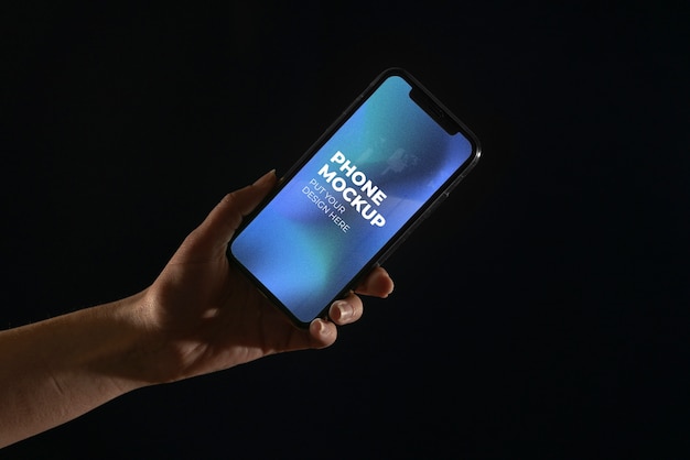 Hand holding smartphone device mock-up on color background