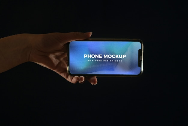Рука держит макет смартфона на цветном фоне