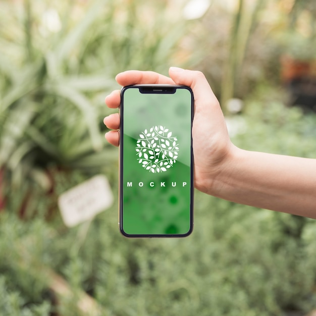 PSD hand holding smartphone mockup with gardening concept