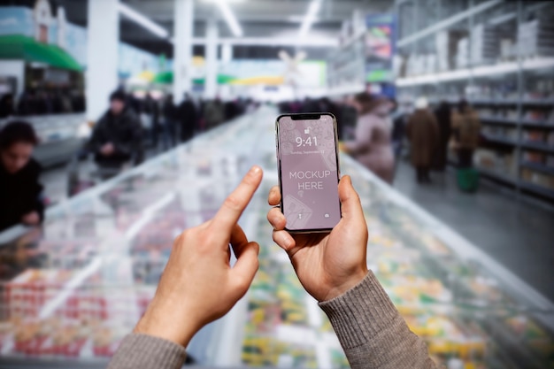 PSD hand holding smartphone in supermarket