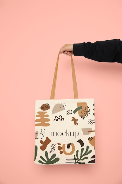 Hand holding tote bag with pink background