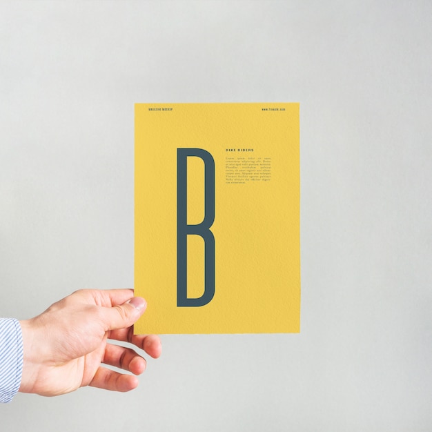 PSD hand holding yellow paper mockup