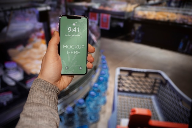 Hand met smartphone in de supermarkt