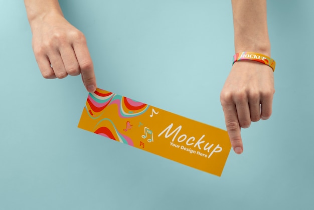 Hand with mock-up music fest bracelet holding concert ticket