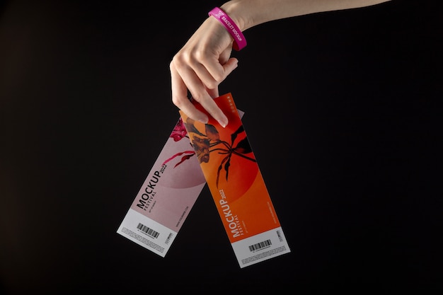 Hand with music fest bracelet holding mock-up tickets