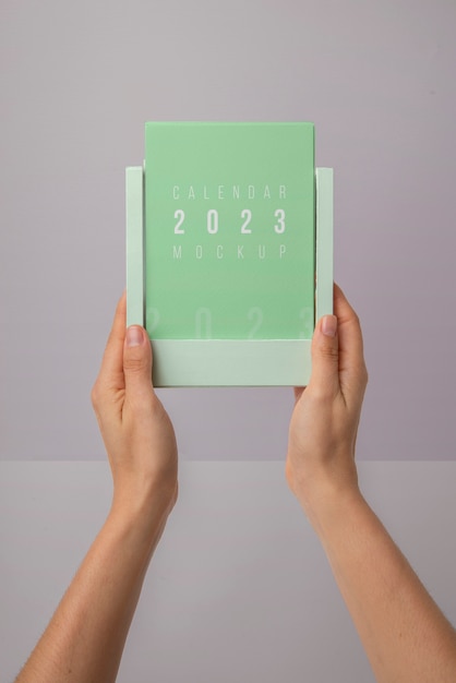 PSD mani che tengono il mockup del calendario