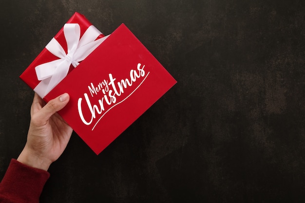 PSD hands holding merry christmas greeting card mockup template and gift box.