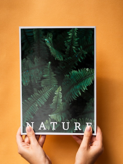 PSD hands holding a nature magazine on a orange background