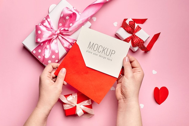 Mani che tengono il mockup di carta di san valentino con scatole regalo