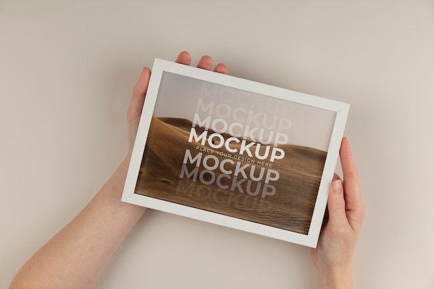 PSD hands holding white frame mockup flat lay